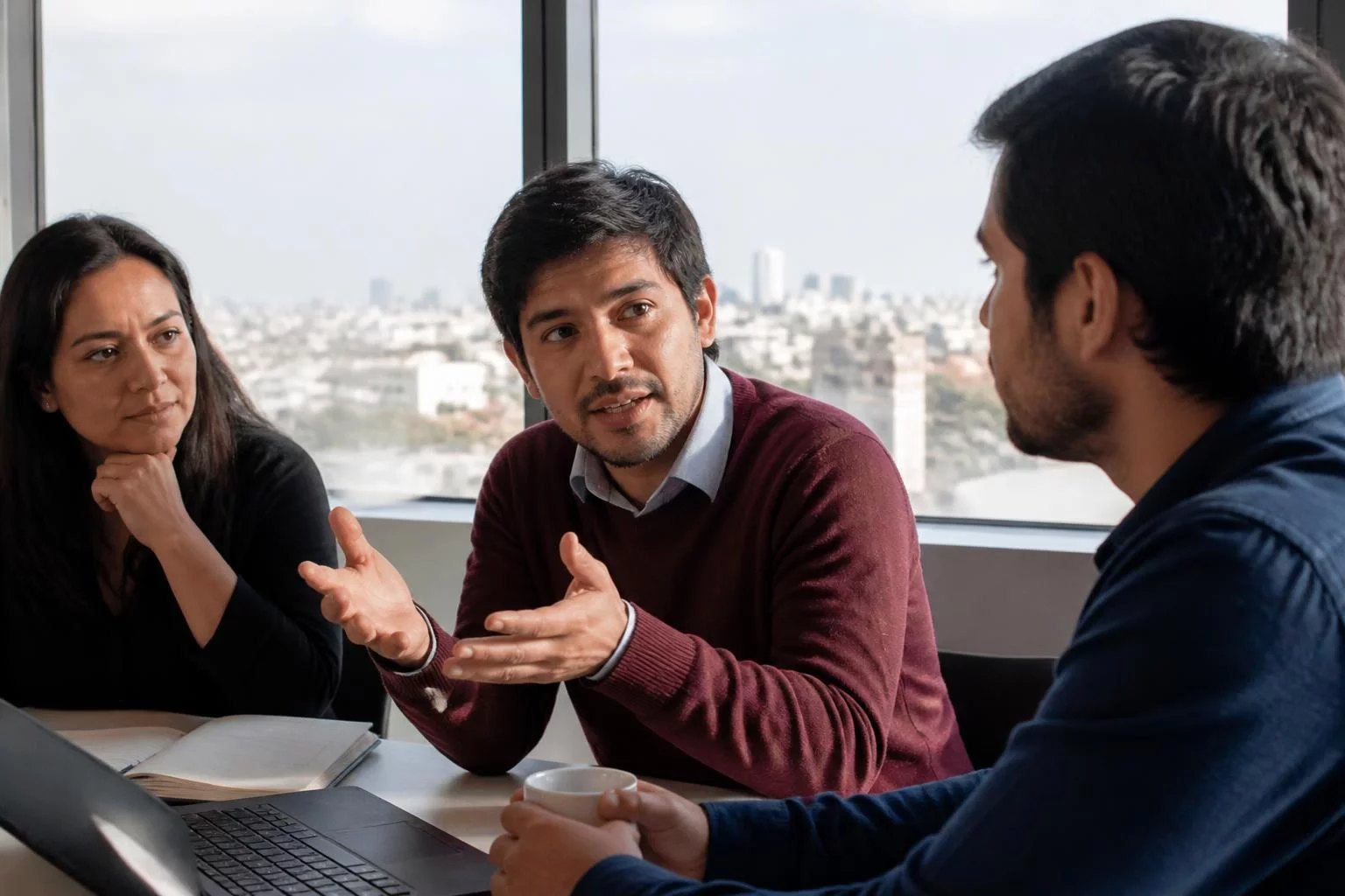 Tres profesionales reunidos, uno sostiene su punto ante los demás